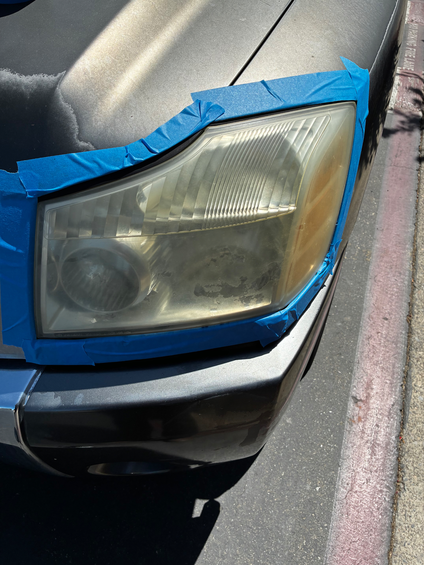 Headlight taped off with painter's tape during Detail X sand-and-polish headlight restoration